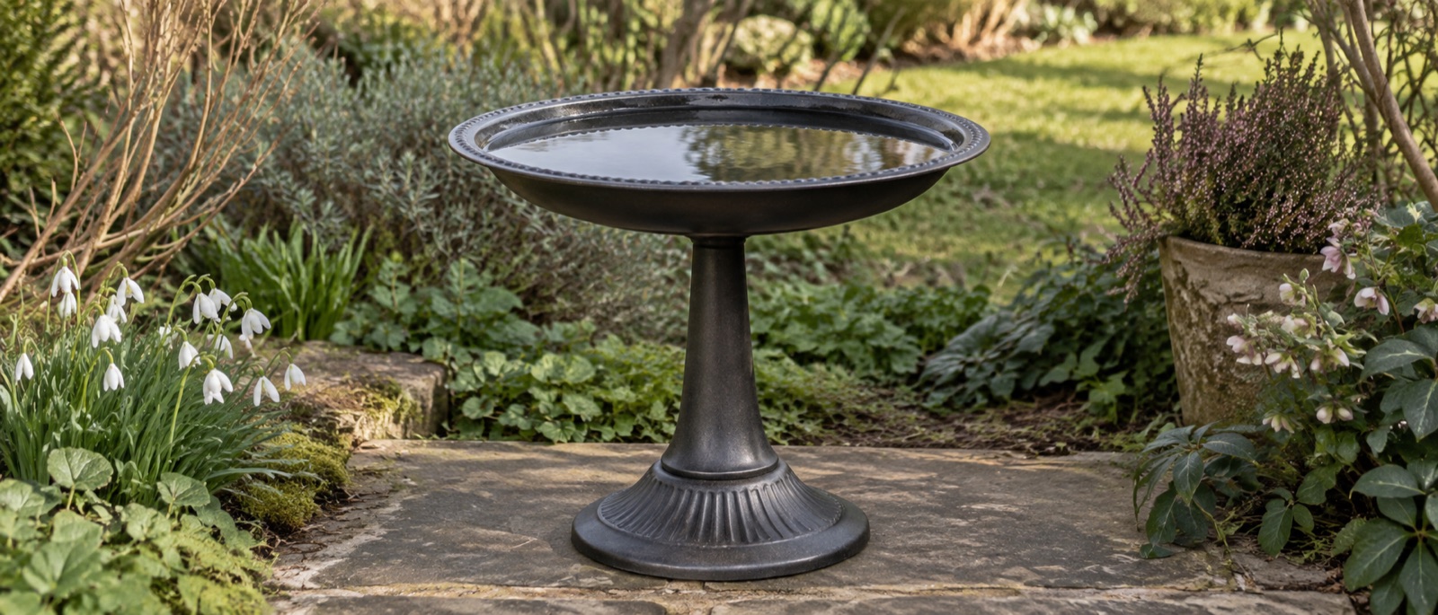 Illustrative metal water bowl on a broad garden stand