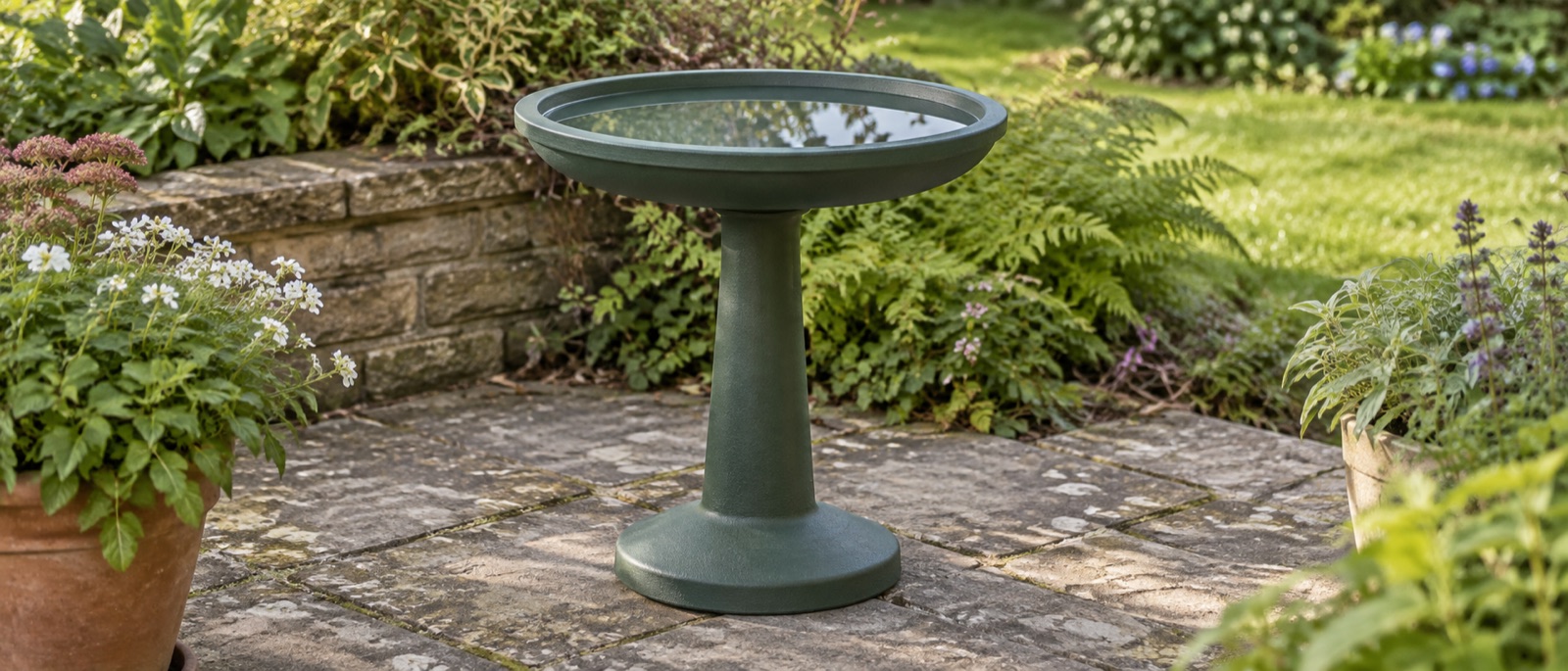 Illustrative green resin pedestal water bowl on paving